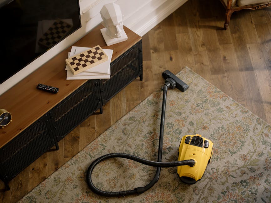 A professional cleaner from Locksbottom Carpet Cleaners is performing deep surface cleaning of a light beige, plush carpet in a bright, modern living room. The cleaner is dressed in a white protective